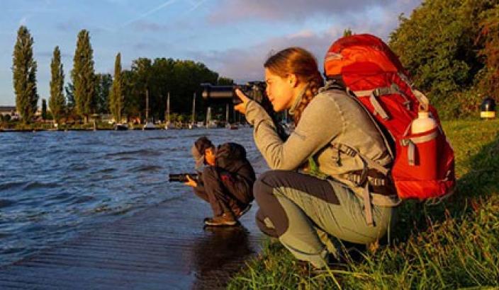 fille prenant une photo au bord du lac