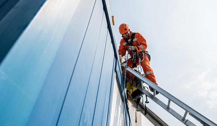 Un ouvrier monte une échelle contre un bâtiment commercial