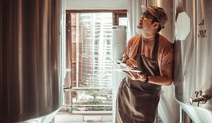 Homme qui se tient à l'intérieur d'une brasserie et vérifie une cuve