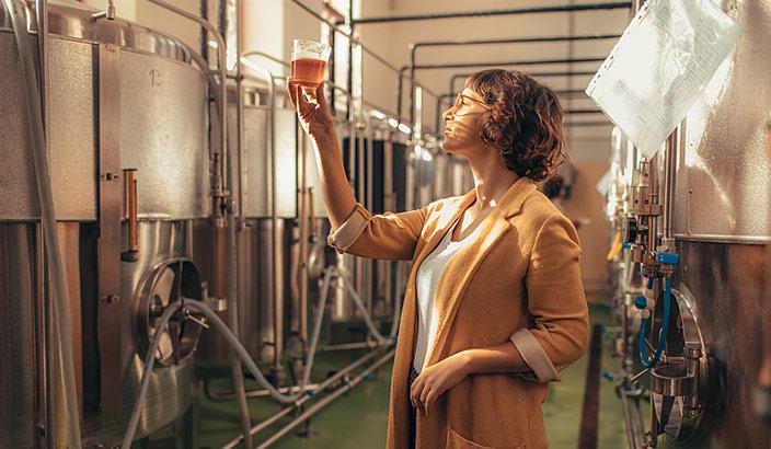 Jeune femme dans une brasserie qui vérifie la qualité d'une boisson