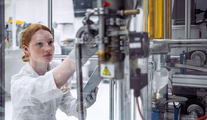 Jeune femme règle une machine industrielle