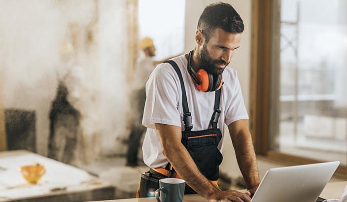 Homme sur un chantier en construction qui consulte son ordinateur