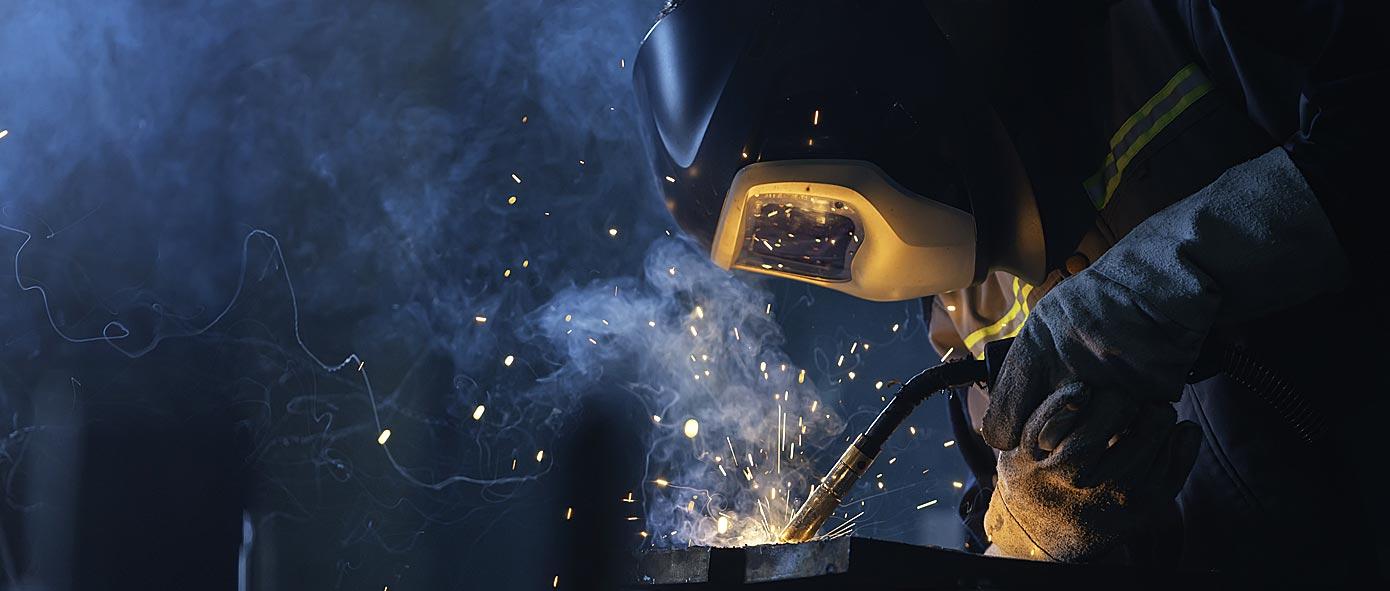 Artisan qui soude une pièce métallique