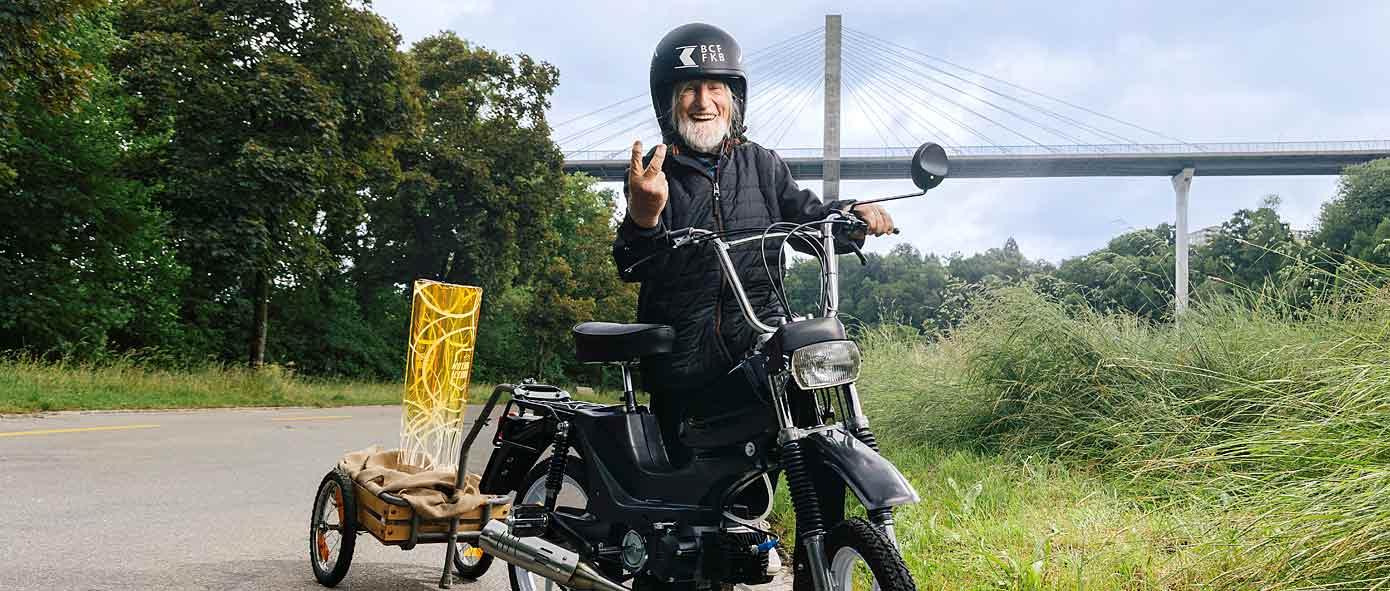 Hubert à côté de son vélomoteur avec un casque et la coupe