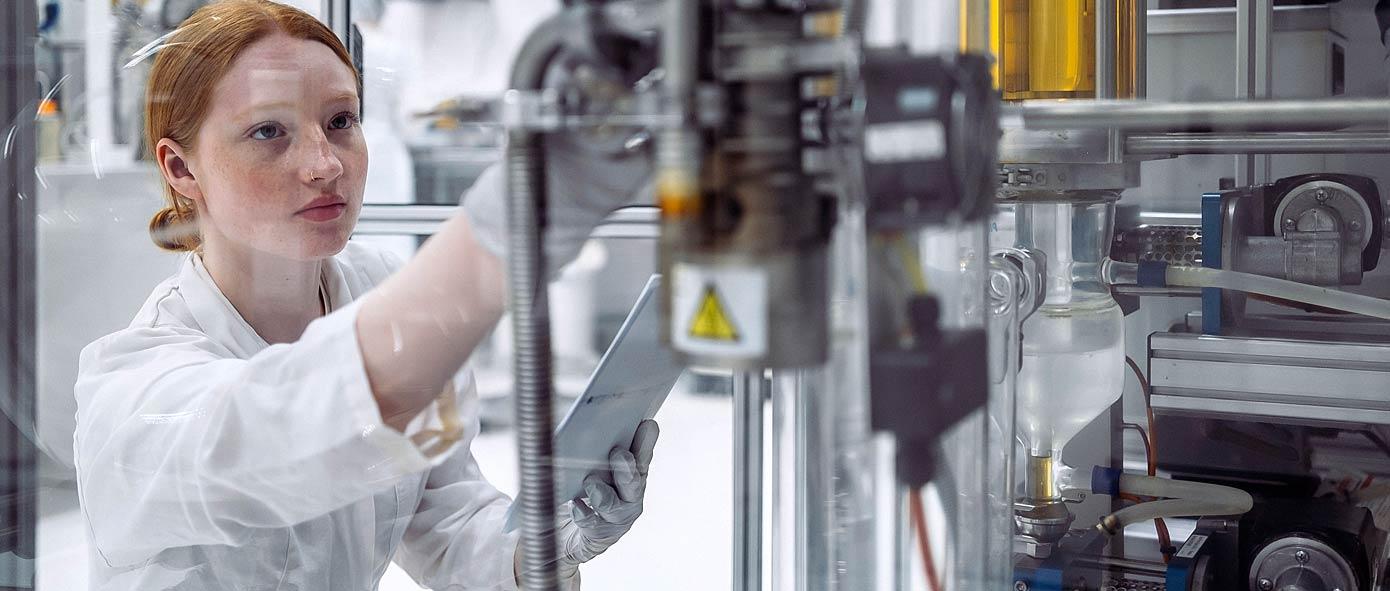 Jeune femme règle une machine industrielle