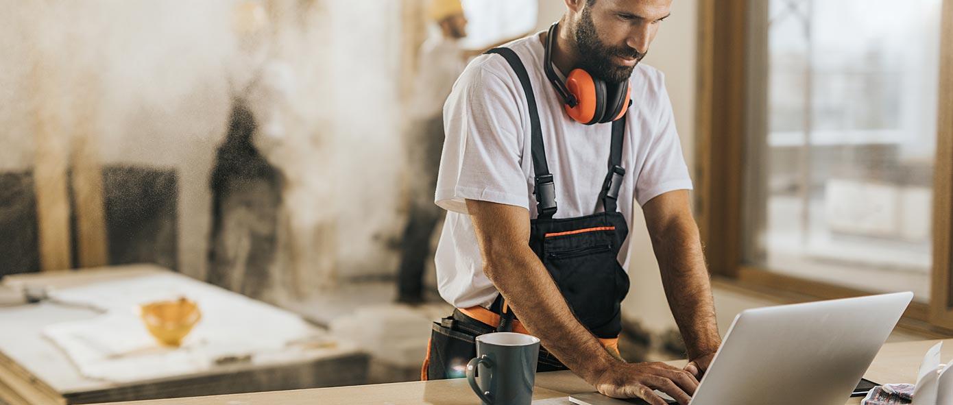 Homme sur un chantier en construction qui consulte son ordinateur